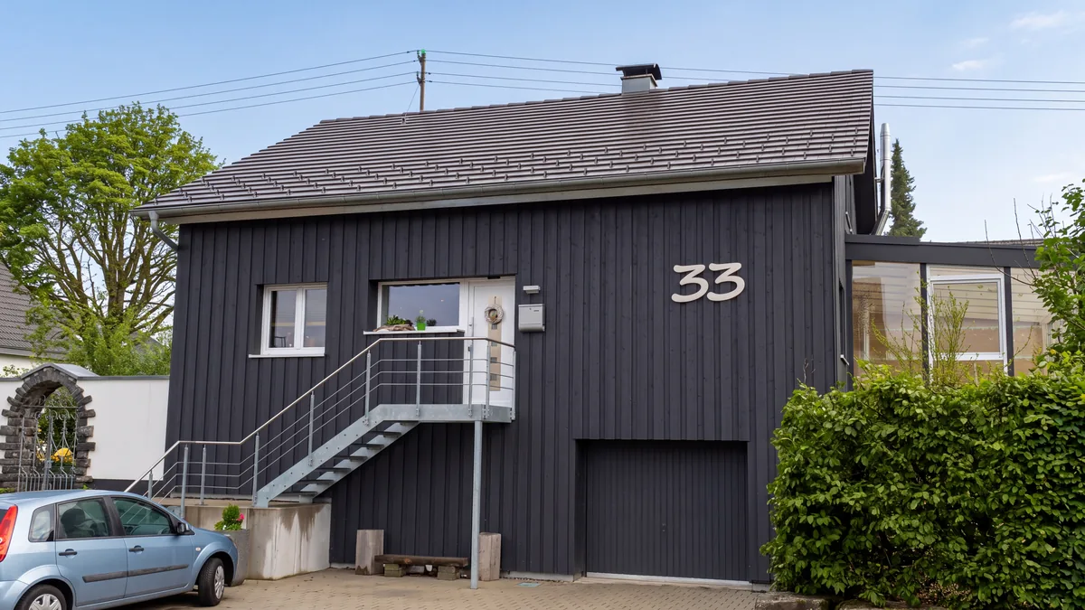 Wohnhaus mit dunkler senkrechter Holzschalung und Außentreppe